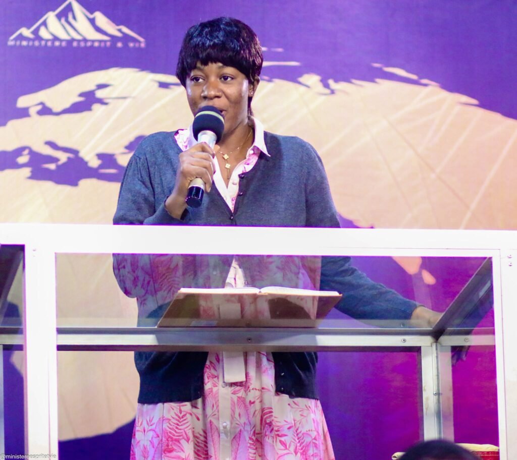 A woman speaking at the podium in front of a world map during an Esprit & Vie gathering